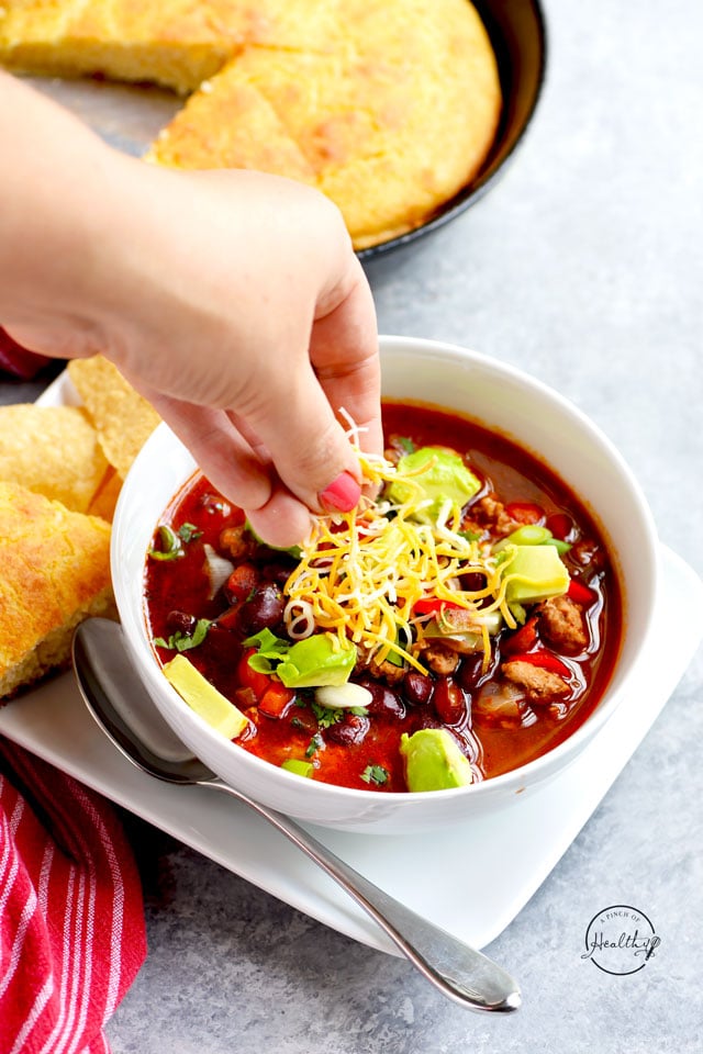 Sprinkling cheese on a bowl of turkey chili