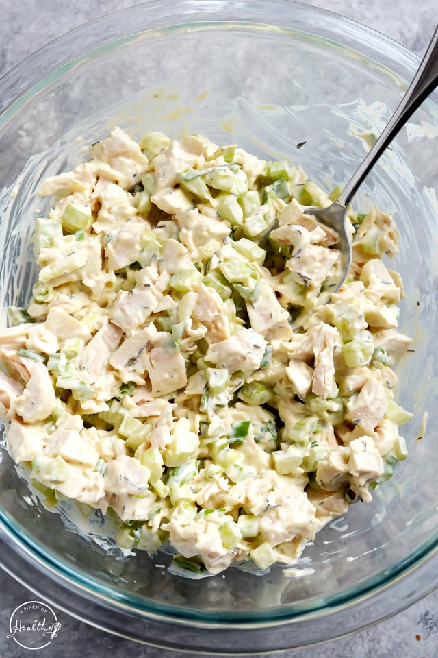 Chicken salad in a clear mixing bowl with spoon