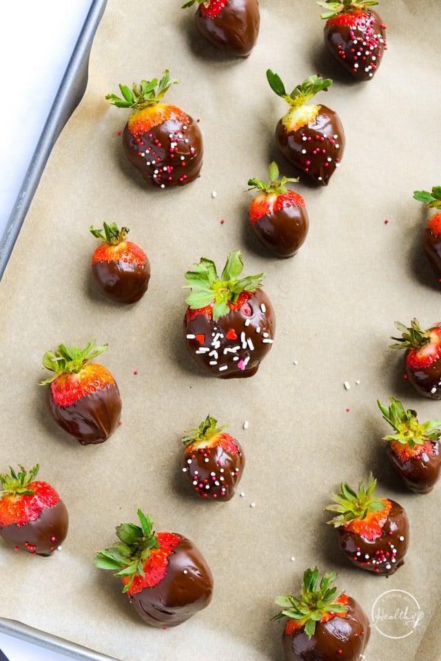 Dark chocolate covered strawberries on a sheet pan with parchment
