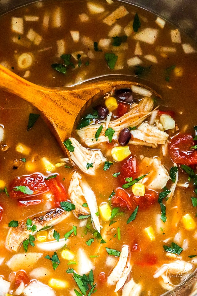 Wooden spoon stirring slow cooker chicken tortilla soup