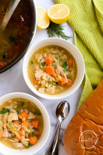 Two bowls lemon chicken orzo soup from overhead with bread