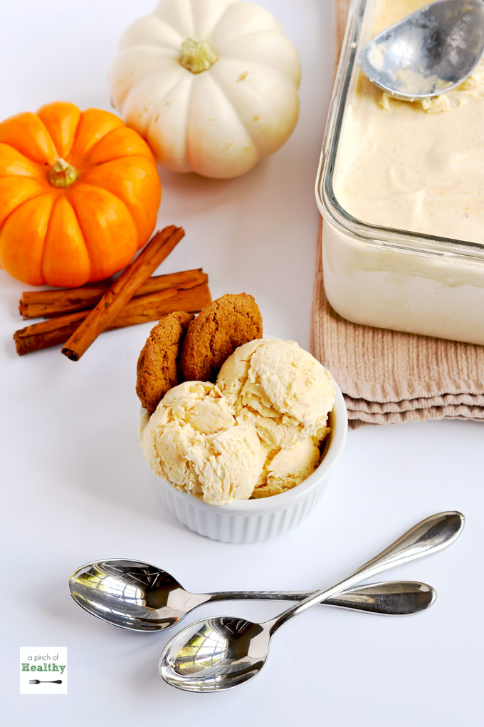 Pumpkin spice ice cream with two spoons and mini pumpkins on white counter