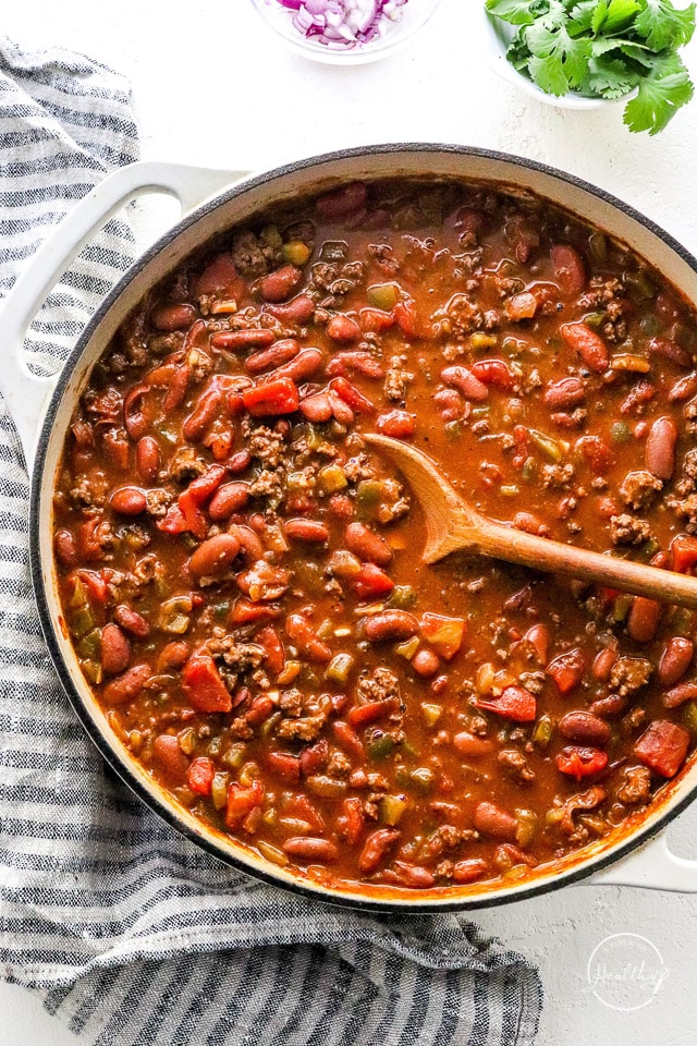 stirring the best chili in a large pot with a wooden spoon