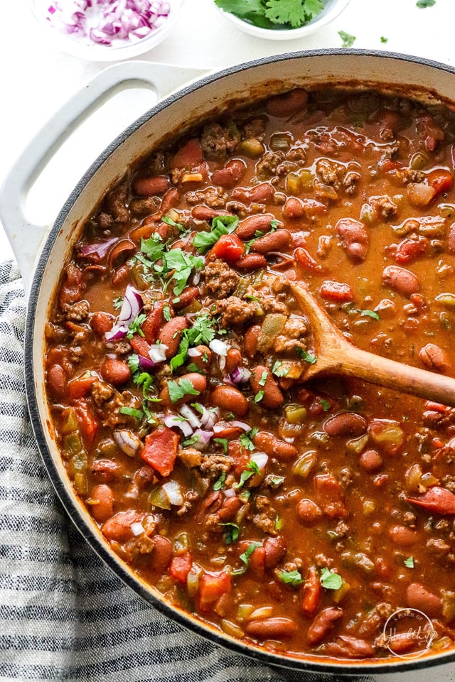 classic beef chili in na big pot with wooden spoon