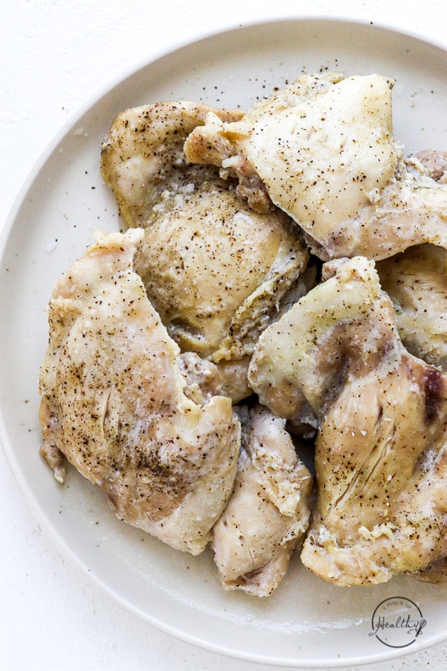 Instant pot chicken thighs on white plate, in preparation for making Instant Pot shredded chicken