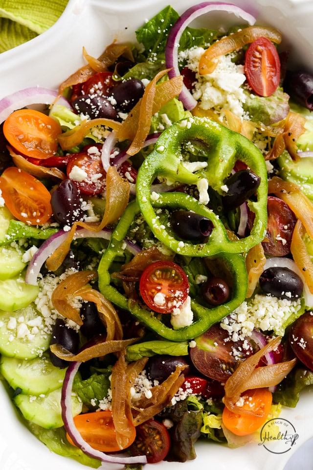 Greek salad with bell pepper rings in decorative white bowl