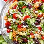 Closeup side shot tossed Greek Pasta Salad in glass bowl