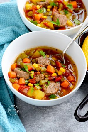 Closeup white bowl with Instant Pot vegetable beef soup and a spoon