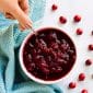 hand serving easy homemade cranberry sauce with a spoon