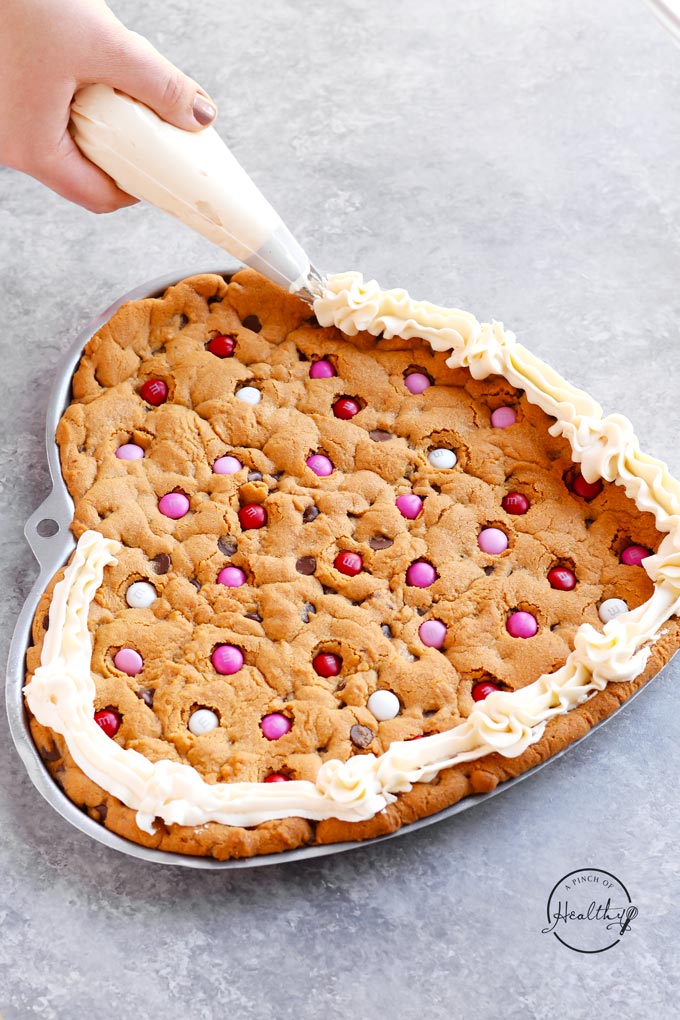 Peanut butter chocolate chip cookie cake with m&ms and buttercream icing - heart shaped for Valentines Day