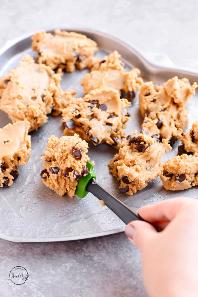 Spooning cookie dough into the prepared heart-shaped baking dish.
