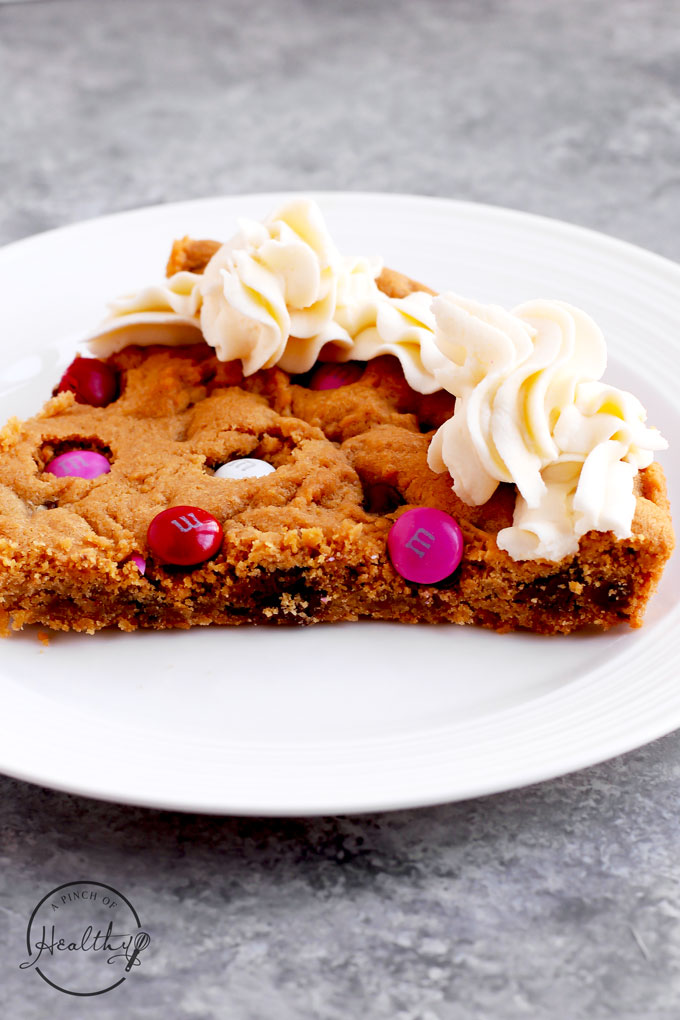 Peanut butter chocolate chip cookie cake with m&ms and buttercream icing - heart shaped for Valentines Day