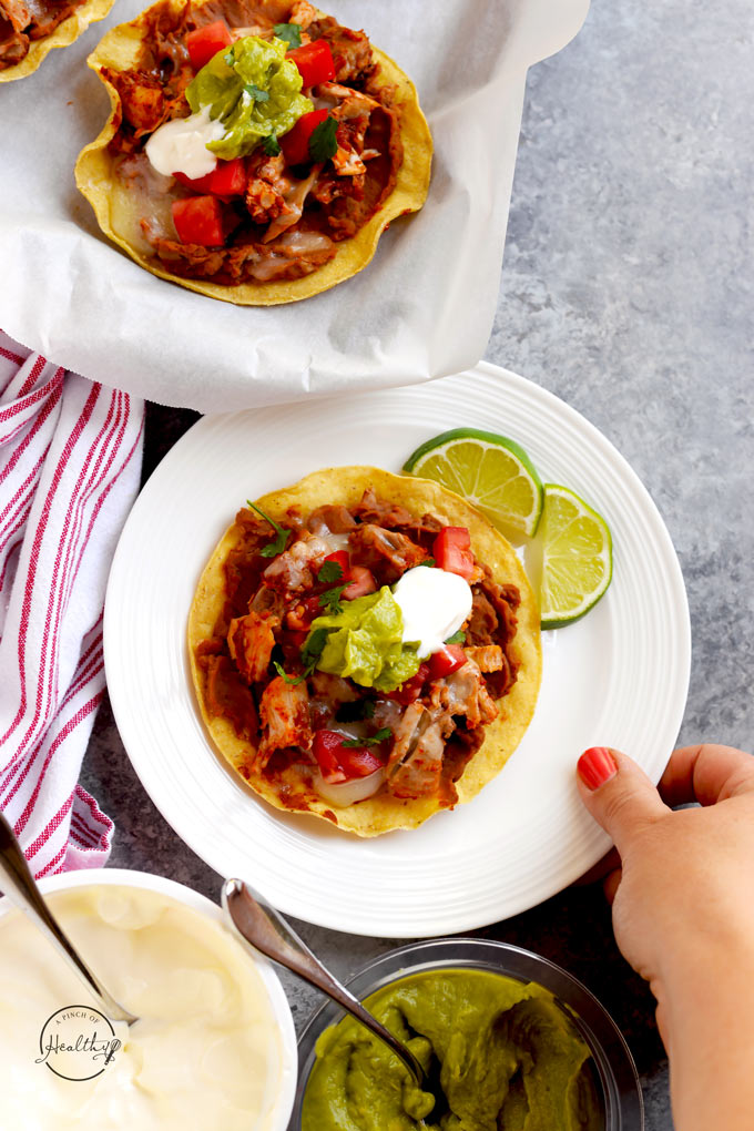 Chicken tostadas with refried beans, chicken, cheese, tomatoes, guacamole and sour cream