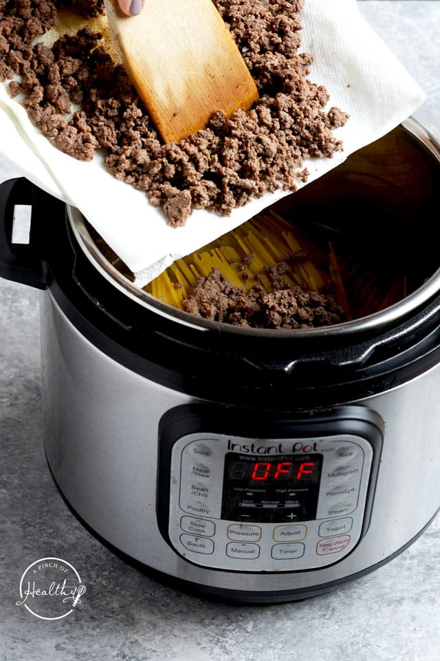 adding ground beef to Instant Pot on top of pasta