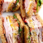 Club sandwich closeup with turkey, ham, bacon, colby jack cheese, lettuce tomato and bacon