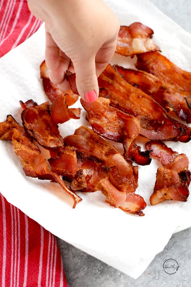 Air fryer bacon with hand grabbing a piece