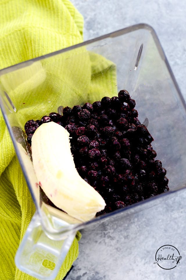 Banana and frozen blueberries in a blender jar