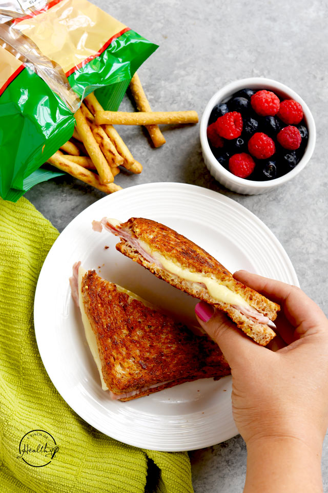 Grilled ham and cheese sandwich with berries and pretzel sticks