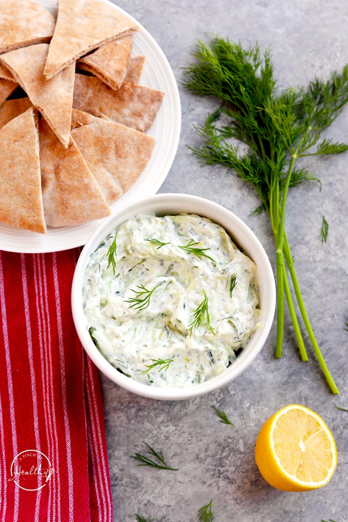 Overhead shot of Tzatziki with dill, soft pita bread and half a lemon