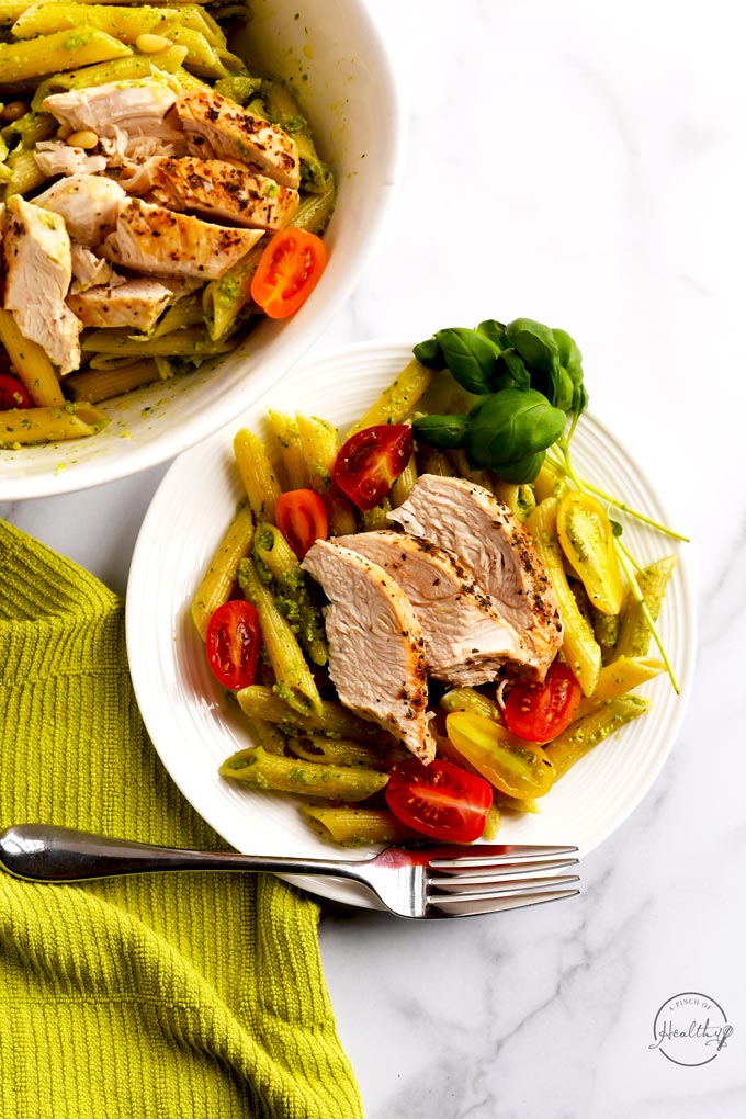 chicken pesto pasta on white plate shot overhead on marble surface