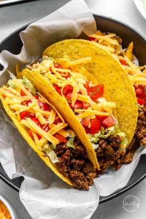 Ground beef tacos in a bowl with white paper liner