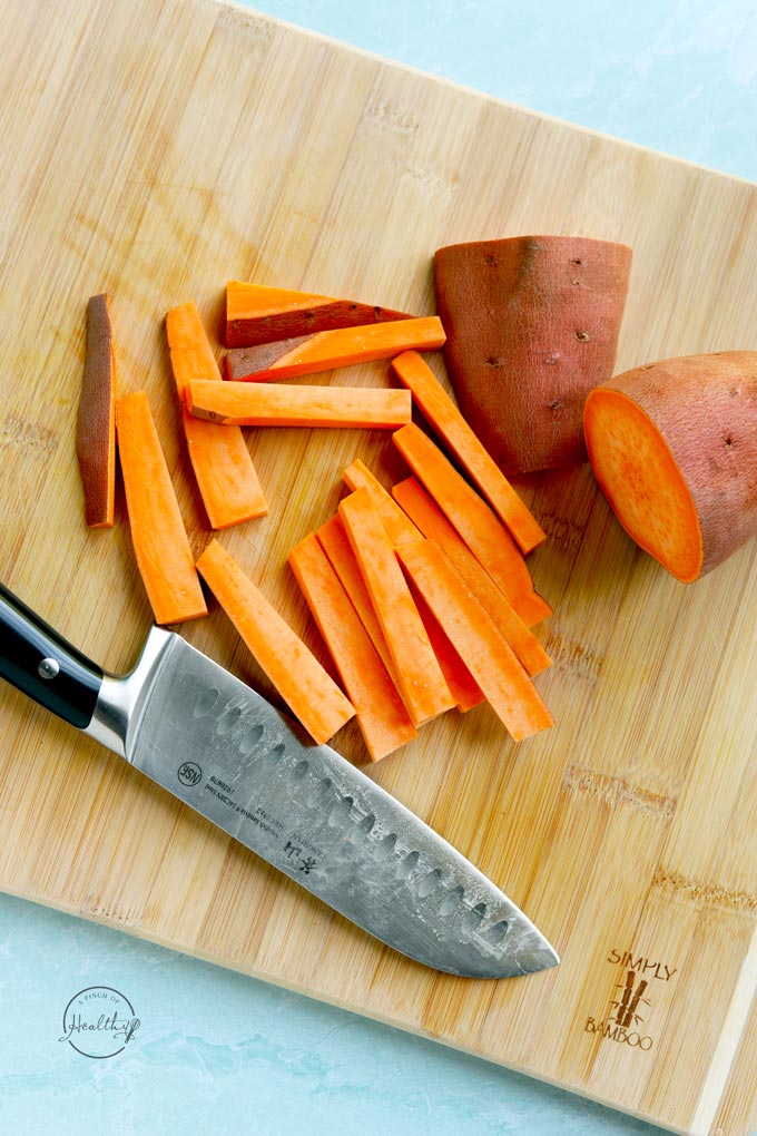 sliced sweet potatoes on a wood cutting board with a knife