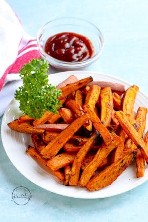 Air fryer sweet potato fries on a white plate with parsley