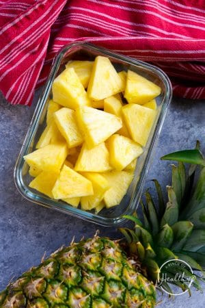 pineapple chunks in clear glass container on gray surface