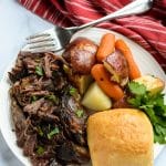 crock pot roast on a white plate with potatoes and carrots
