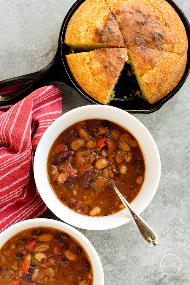 Instant pot vegetarian chili in a white bowl with a skillet of cornbread