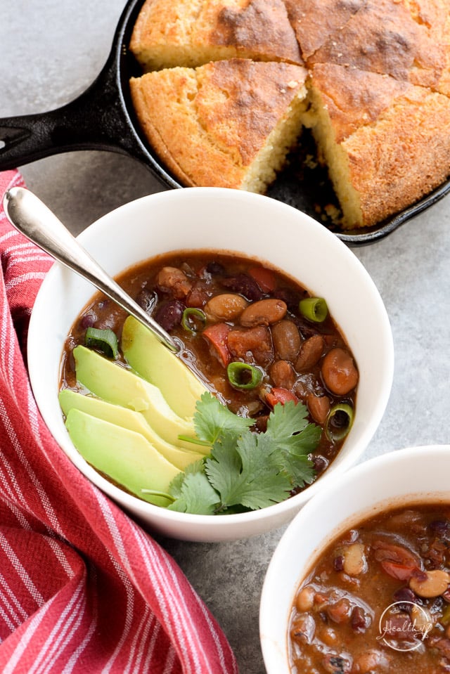 Instant Pot vegetarian chili with cilantro and avocado slices in a white bowl