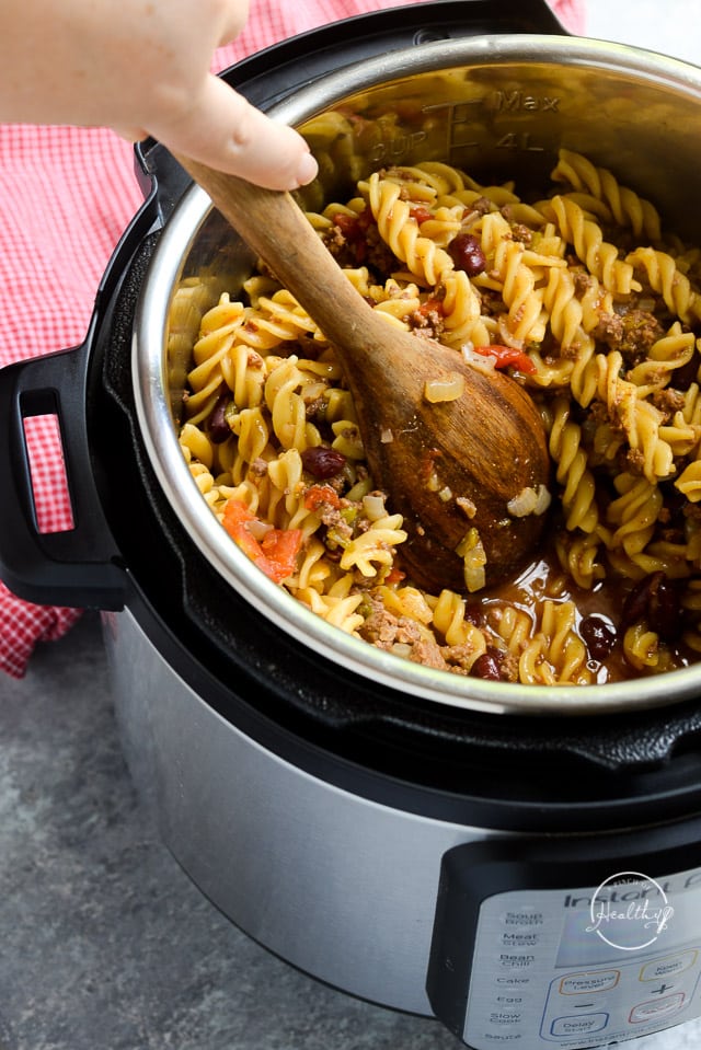 stirring Instant Pot chili mac with wooden spoon
