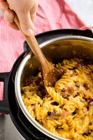 serving chili mac from the Instant Pot with a wooden spoon