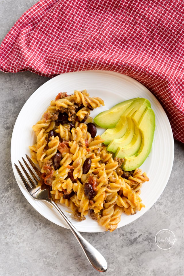 overhead view of white plate with Instant Pot chili mac and cheese with a side of avocado slices