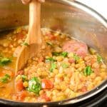 Wooden spoon stirring lentil soup in the Instant Pot