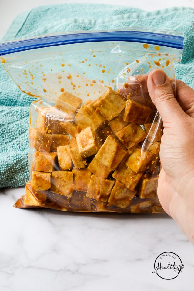 hand holding a freezer bag of marinated tofu