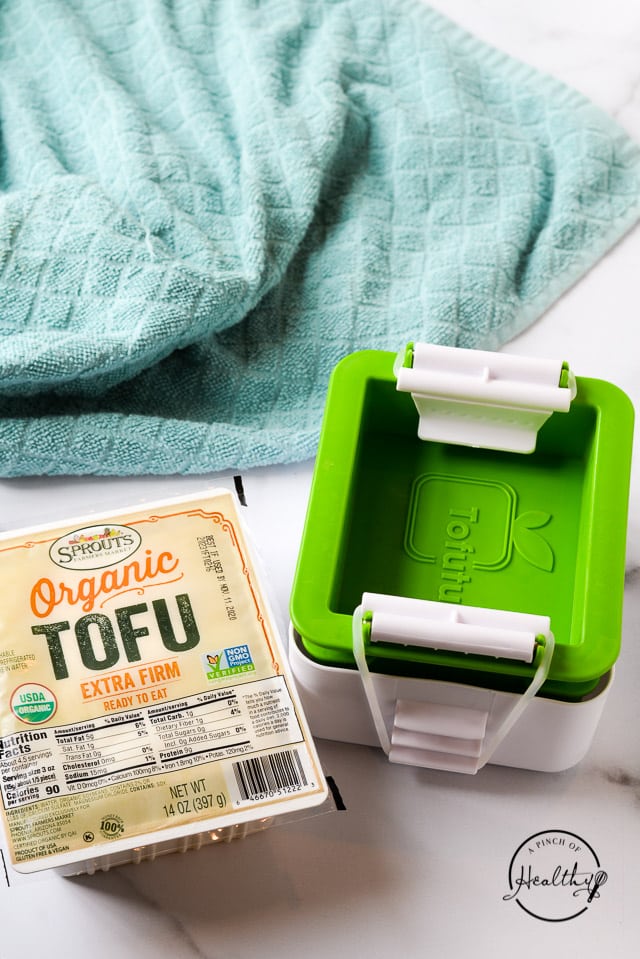 Organic tofu and tofu press next to a blue kitchen towel