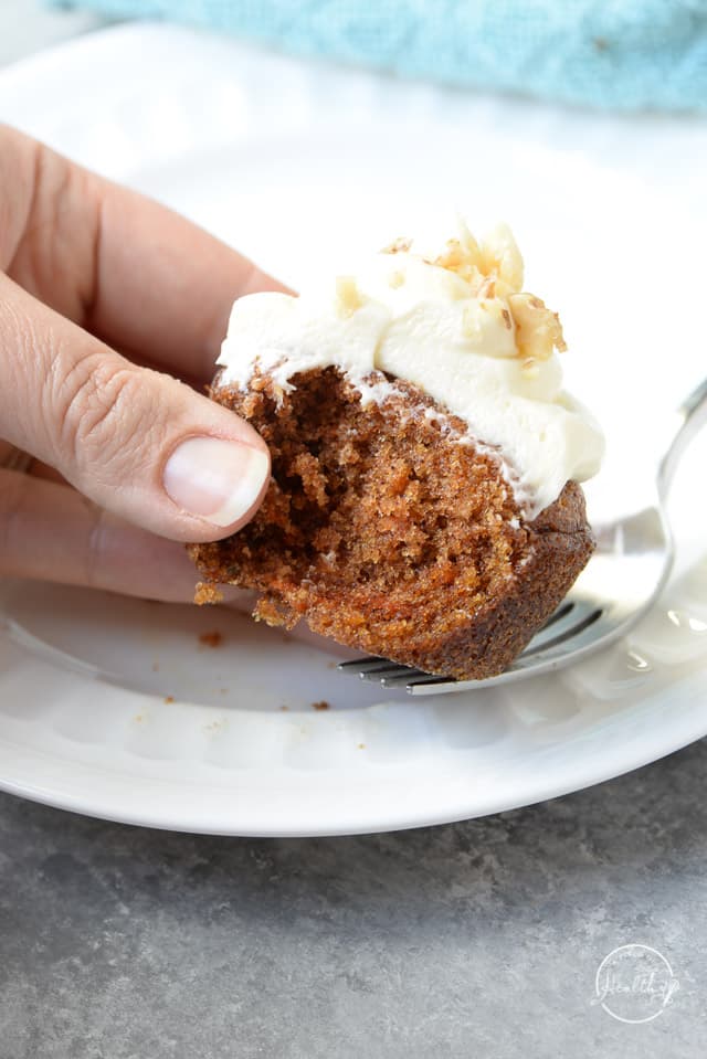 hand holding a carrot cake cupcake that shows perfect texture of the inside