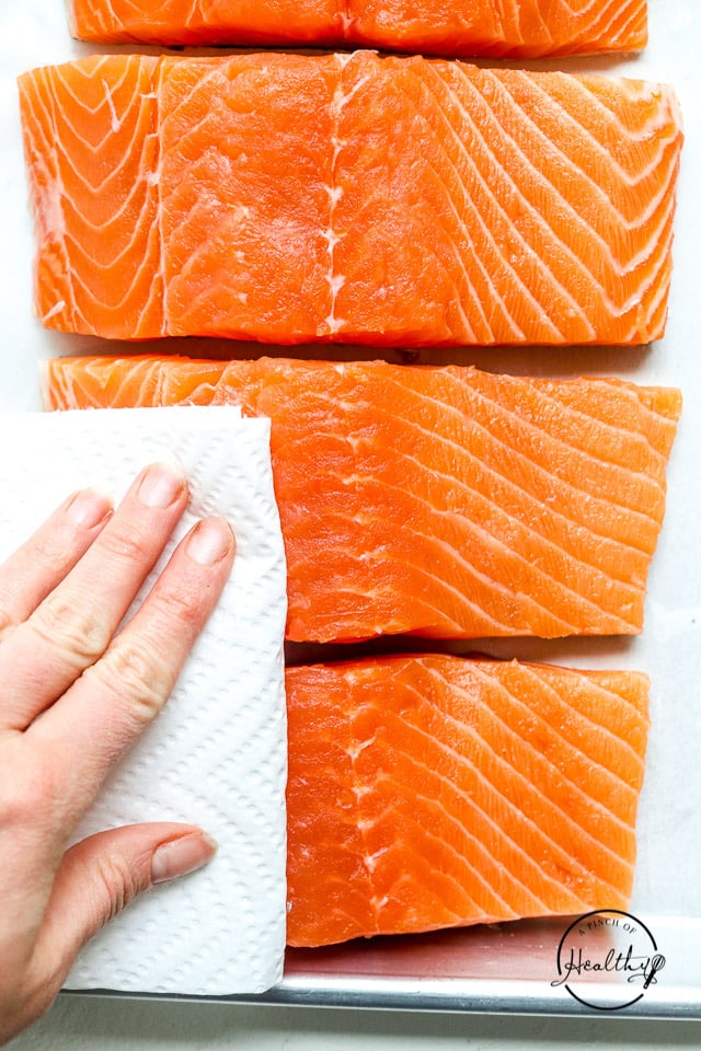 hand patting fish dry with paper towel