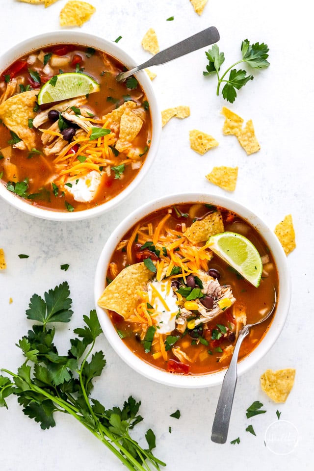 two bowls of slow cooker chicken tortilla soup overhead in white bowls