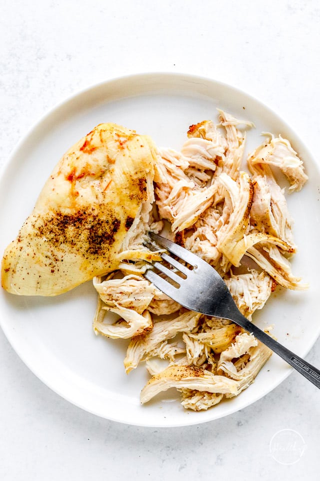 shredded chicken on a white plate with a fork