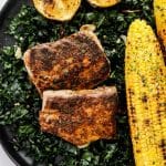 blackened mahi mahi on a plate with kale and grilled corn on the cob