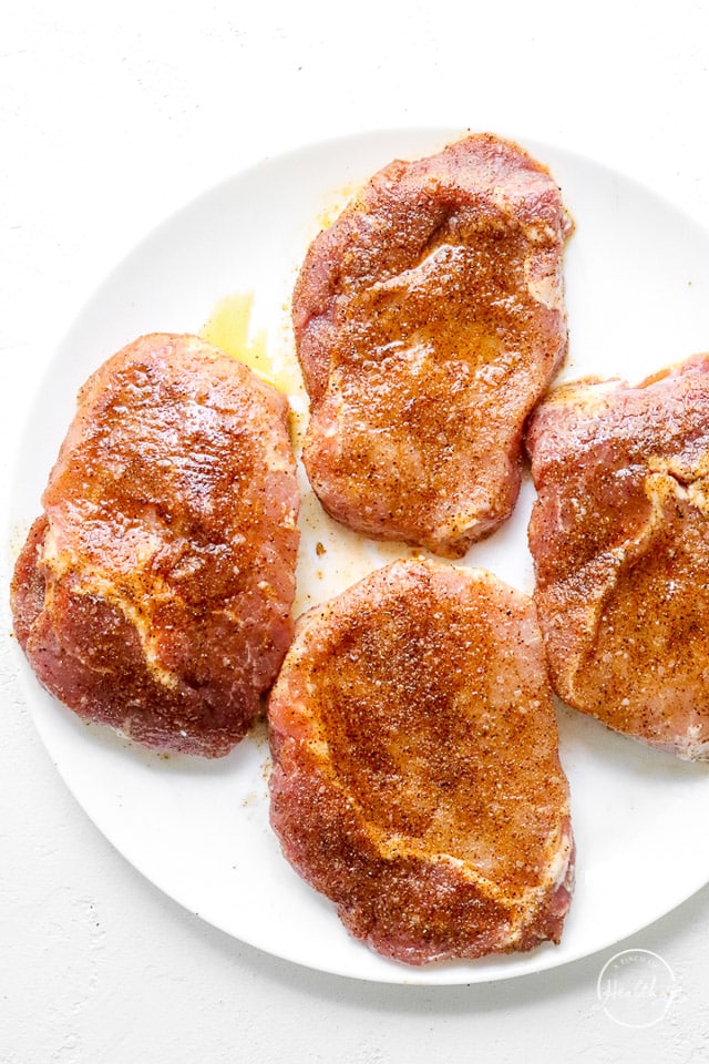 4 pieces of raw, seasoned meat on a white plate