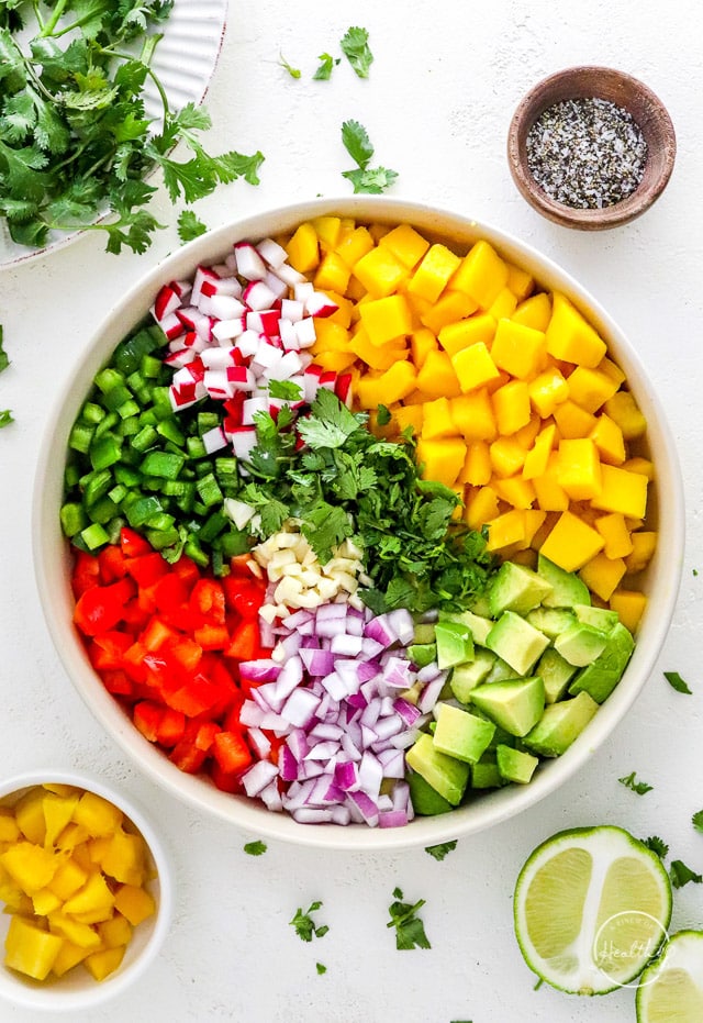fruit, veggies and cilantro added to a large mixing bowl