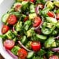 Closeup of tomato cucumber avocado salad in white serving bowl