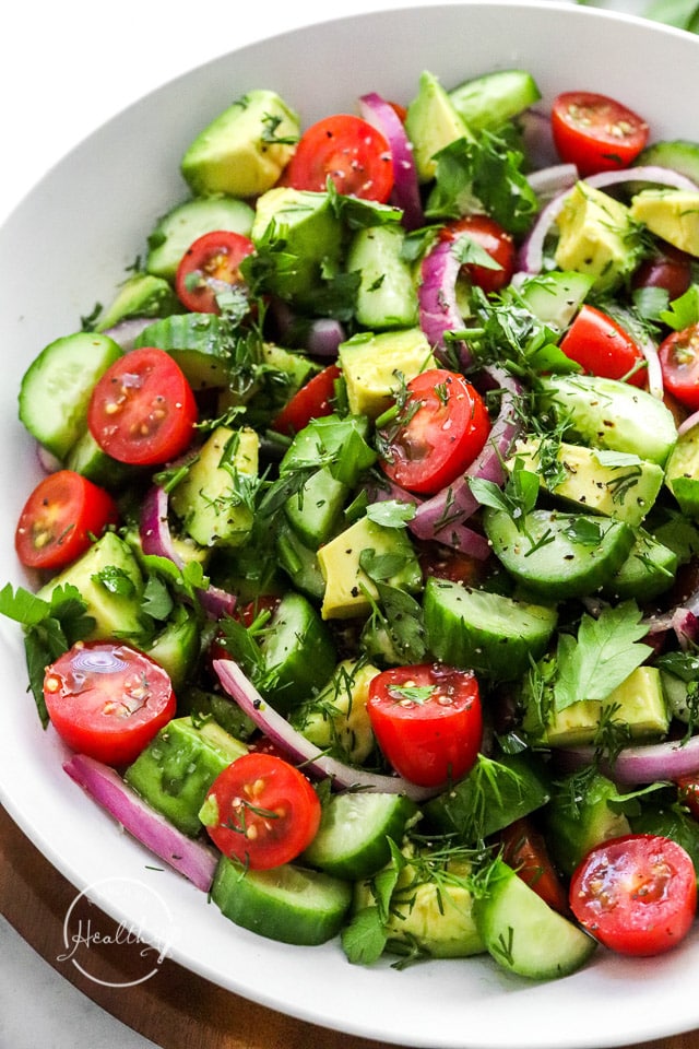 Closeup of tomato cucumber avocado salad in white serving bowl