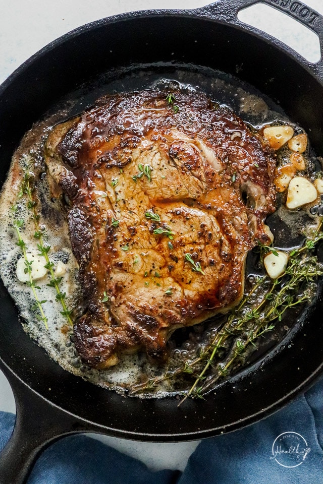 Cast iron steak with sliced garlic, melted butter and herbs