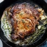 steak cooking in cast iron pan with herbs and melted butter