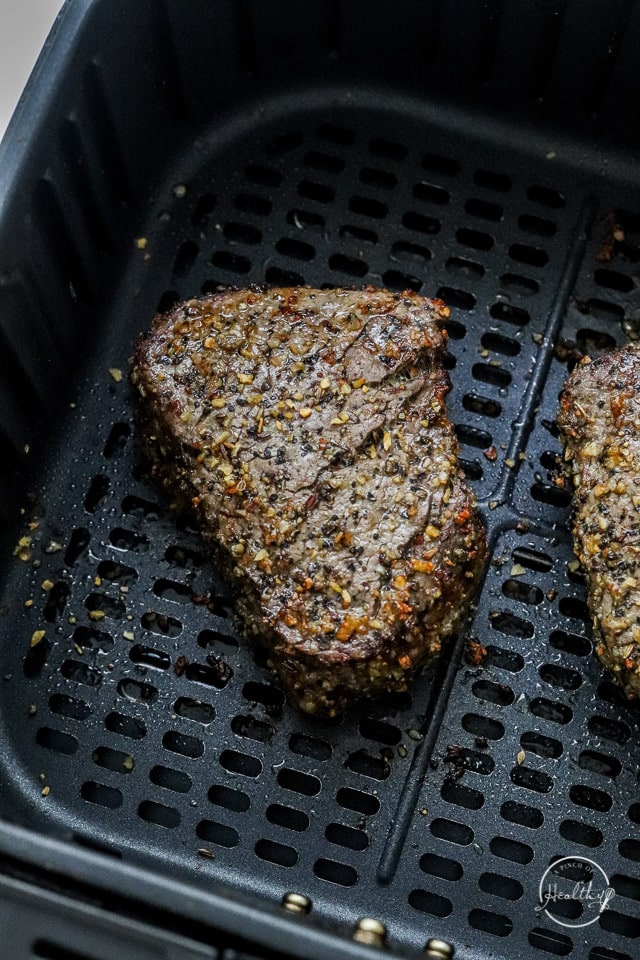 cooked filet steak in the air fryer basket