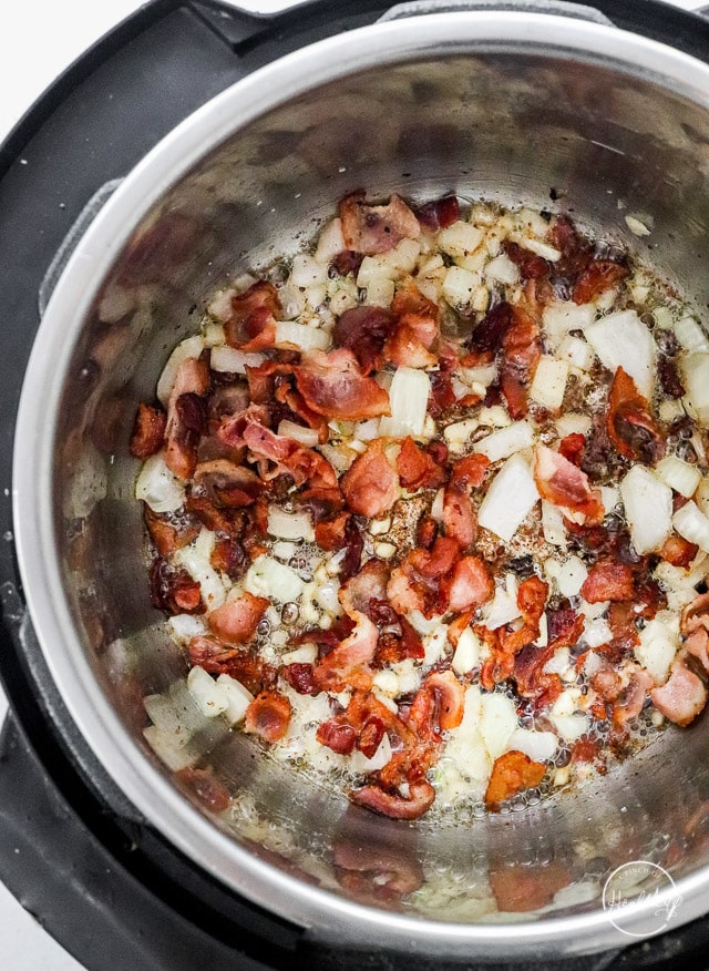 cooking bacon and onion in a stainless pot